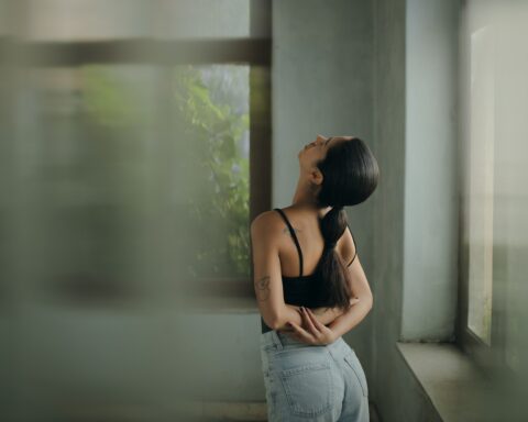 A woman leaning against a wall with her head in her hands