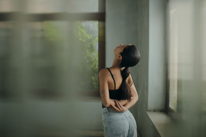 A woman leaning against a wall with her head in her hands