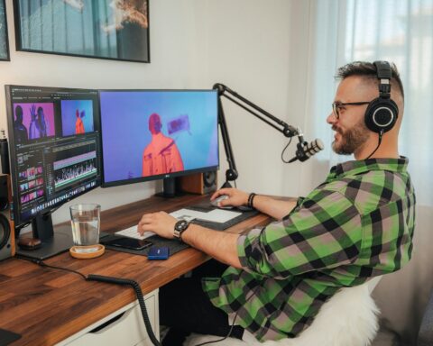 a man wearing headphones and sitting at a desk with a computer