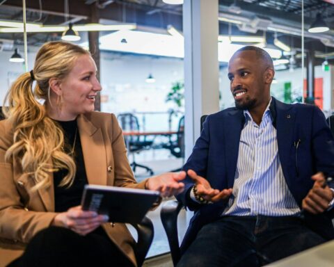 man in black suit jacket sitting beside woman in brown blazer